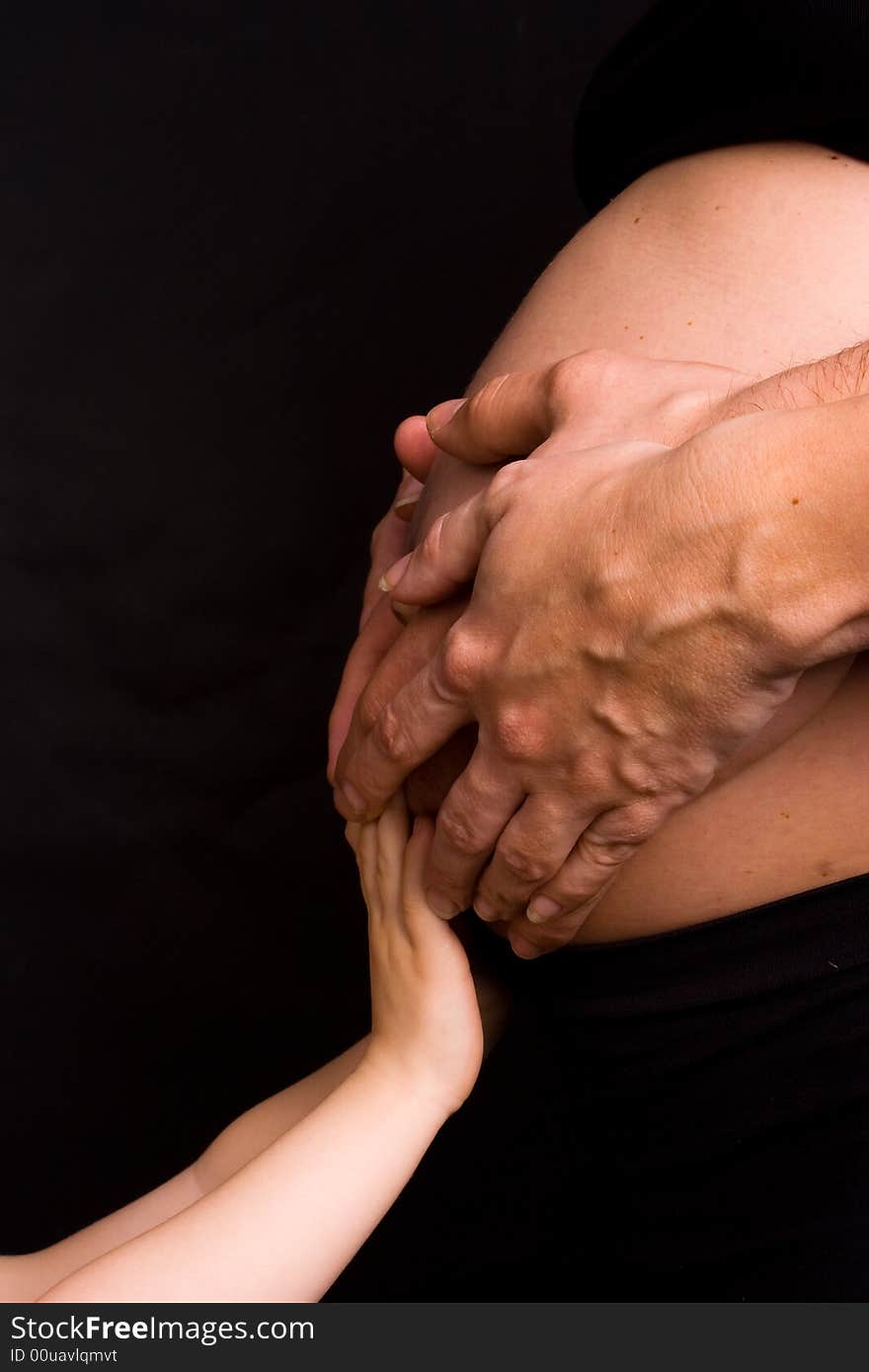 Hands of parents and child on pregnant belly