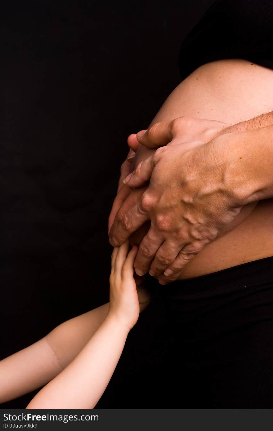 Hands of parents and child on pregnant belly