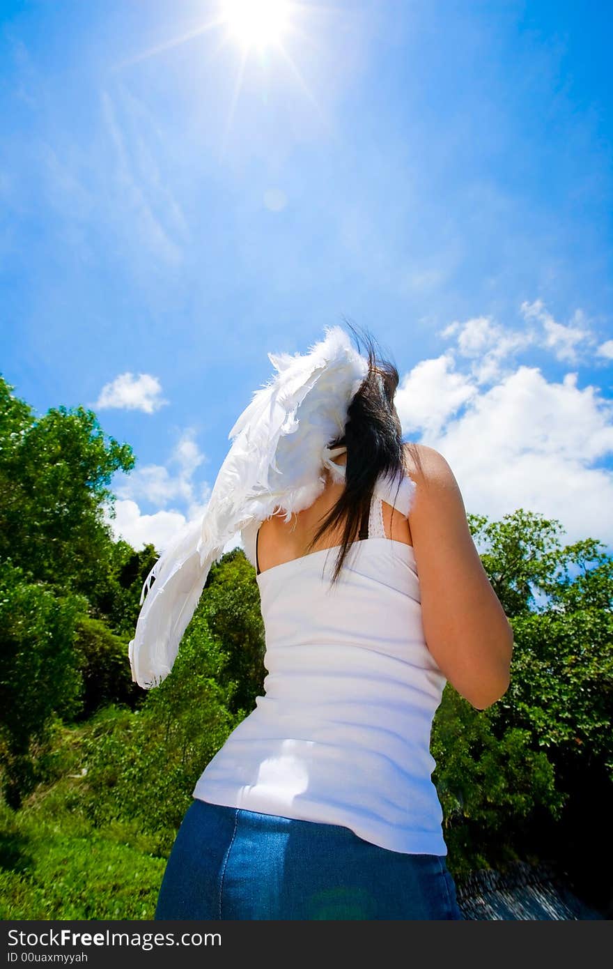 Woman with white angel wings looking up beautiful bright blue sky. Woman with white angel wings looking up beautiful bright blue sky