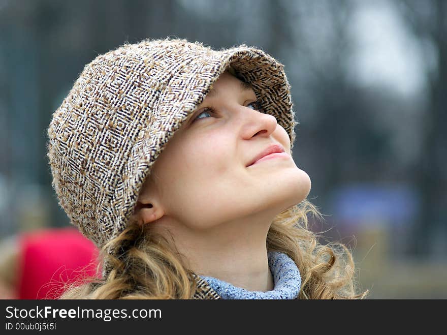 The beautiful girl in a cap looks upwards