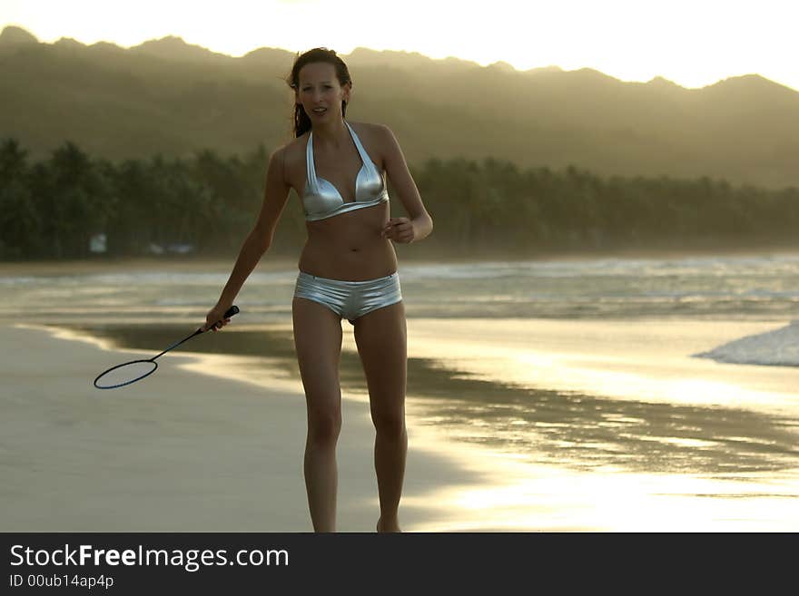 Woman in bikini plays badminton on the beach. Woman in bikini plays badminton on the beach