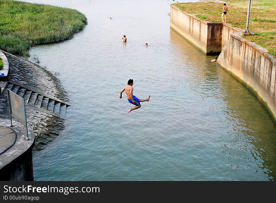 A young man jumping into a river by the village in a hot summer afternoon,Foshan,Guangdong,China,Asia. A young man jumping into a river by the village in a hot summer afternoon,Foshan,Guangdong,China,Asia.