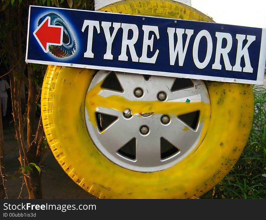 A yellow tyre hunged up outside a tyre work shop