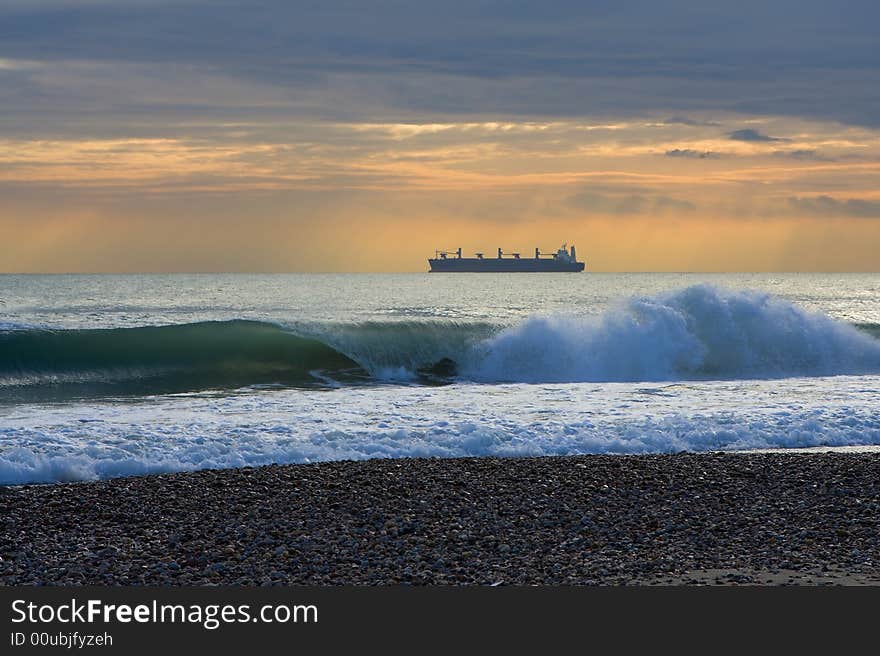 A ship in front of the beach under the clouds. A ship in front of the beach under the clouds