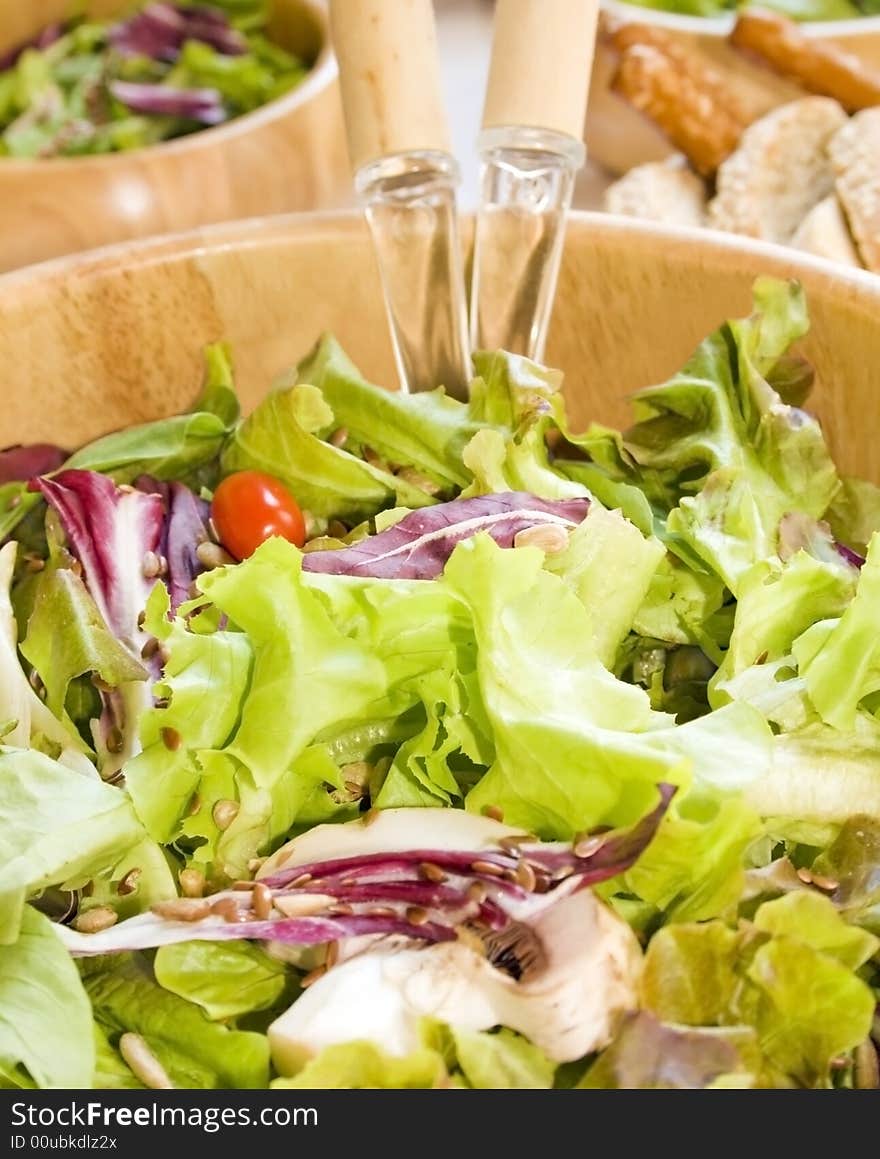 Green salad close up in a wooden salad bowl containing lettuce, arugula (roket), radicchio (chicory), cherry tomato, flax and sunflower seeds. Green salad close up in a wooden salad bowl containing lettuce, arugula (roket), radicchio (chicory), cherry tomato, flax and sunflower seeds.