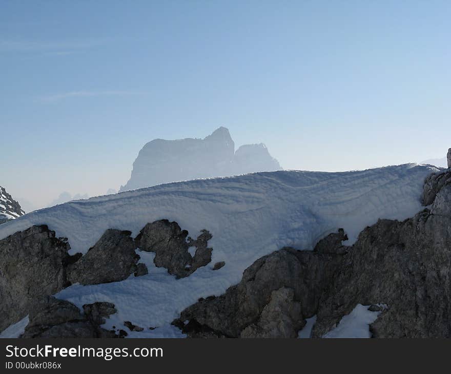 Dolomite rock covered with snow and Pelmo peak in  the background. Dolomite rock covered with snow and Pelmo peak in  the background