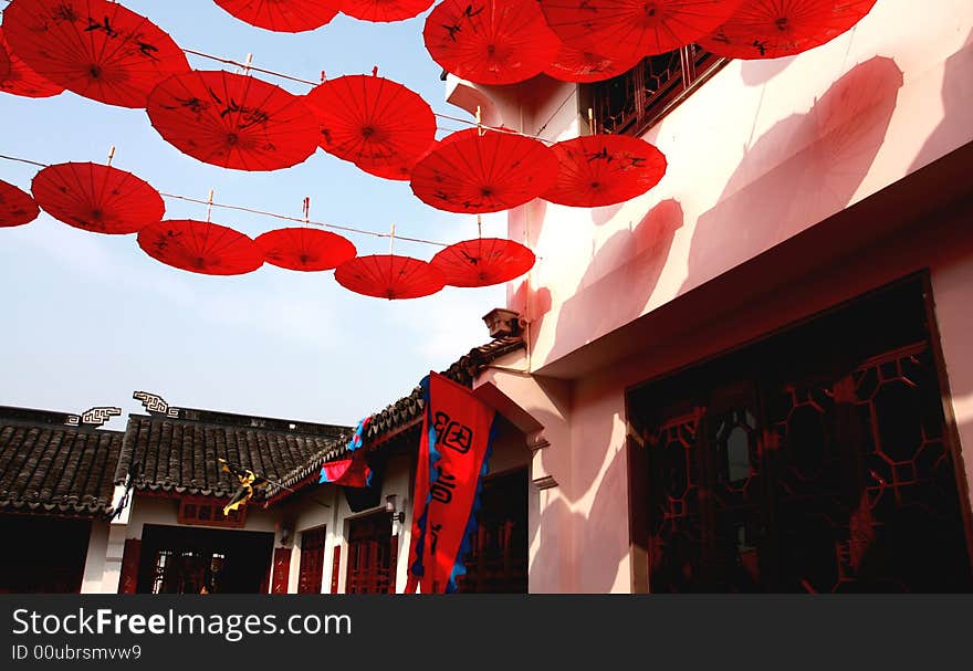 An old chinese traditonal shoping street, decorated by red ambrella, red colour represent happiness, joyful, lucky,atc.