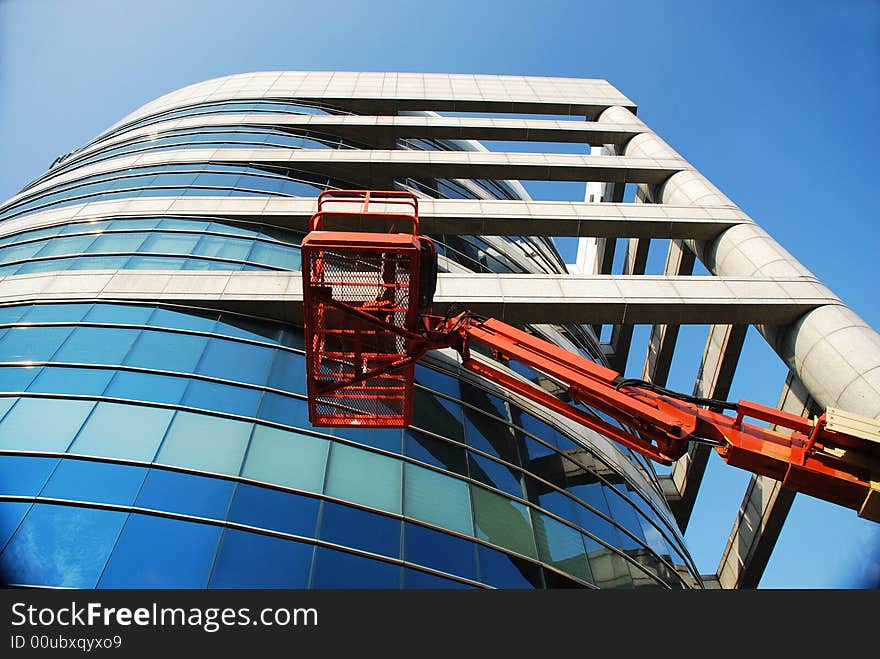 Huge glass building with crane & blue sky