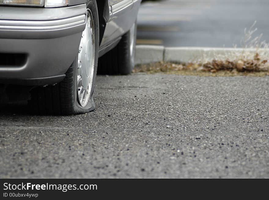 Car parked on a roadway with a flat tire