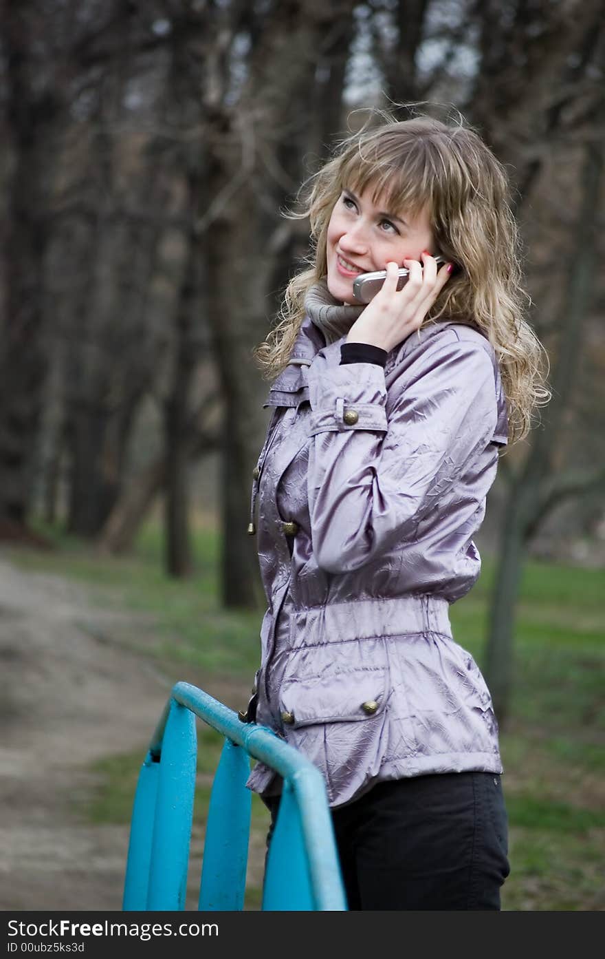 Girl speaks by phone in park. Girl speaks by phone in park