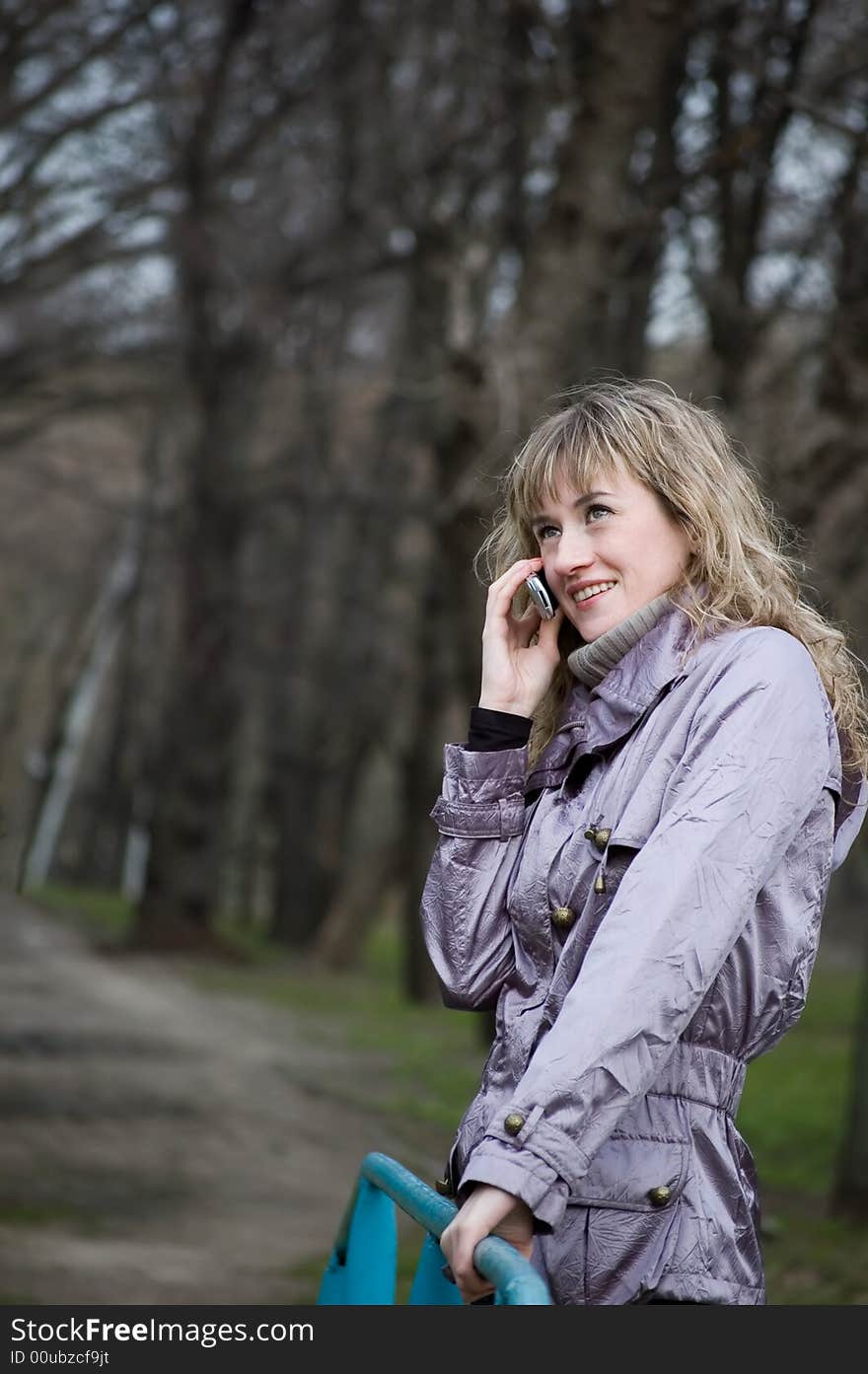 Girl speaks by phone in park. Girl speaks by phone in park