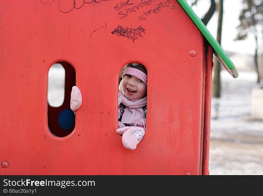 Little happy girl play hide-and-seek at the kindergathen playground. Russian winter. Little happy girl play hide-and-seek at the kindergathen playground. Russian winter