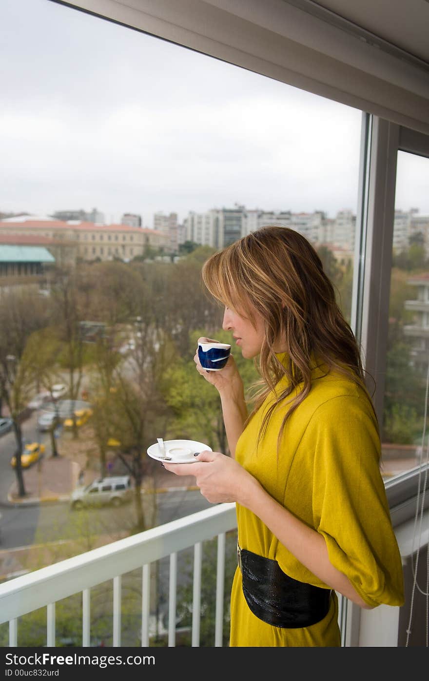 A women is tasting coffee by a window. A women is tasting coffee by a window