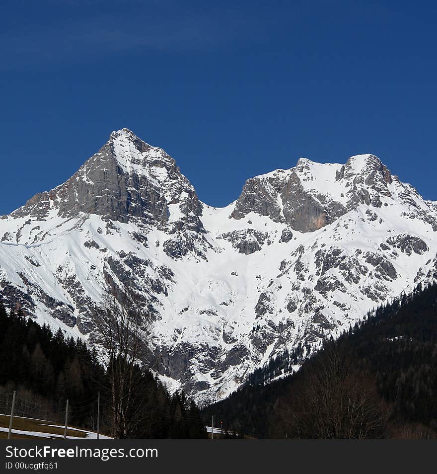 Two peaks of mountain at the background of blue sky .  Alpes in Austria . The Snow on the Rocks. Two peaks of mountain at the background of blue sky .  Alpes in Austria . The Snow on the Rocks.