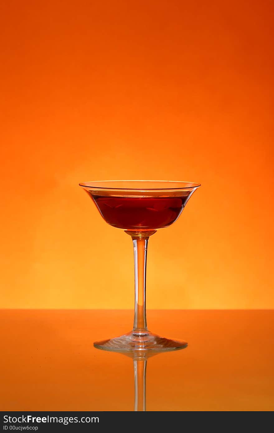 Glass of liqueur over orange background