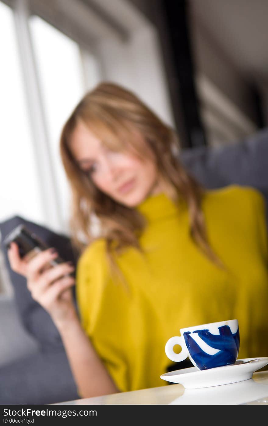 Woman talks on the phone (focus on the cup of coffee)