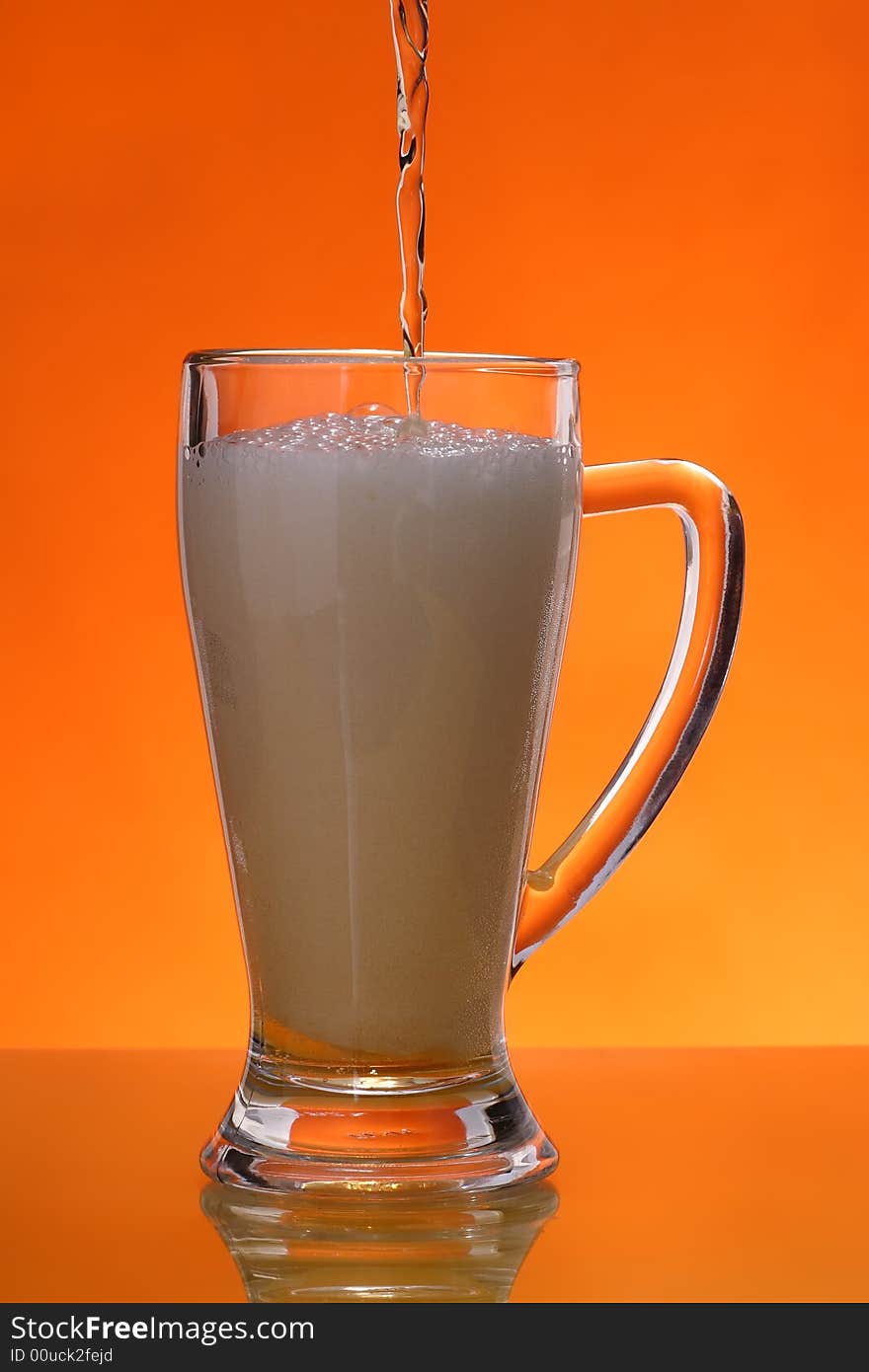 Pouring beer into gass over orange background