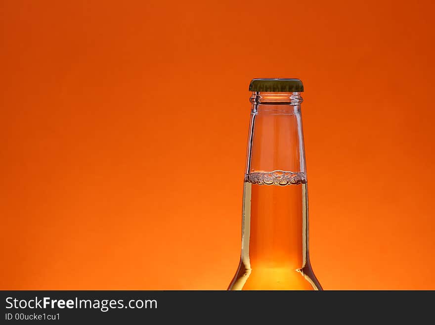 Close up of beer bottle over orange background