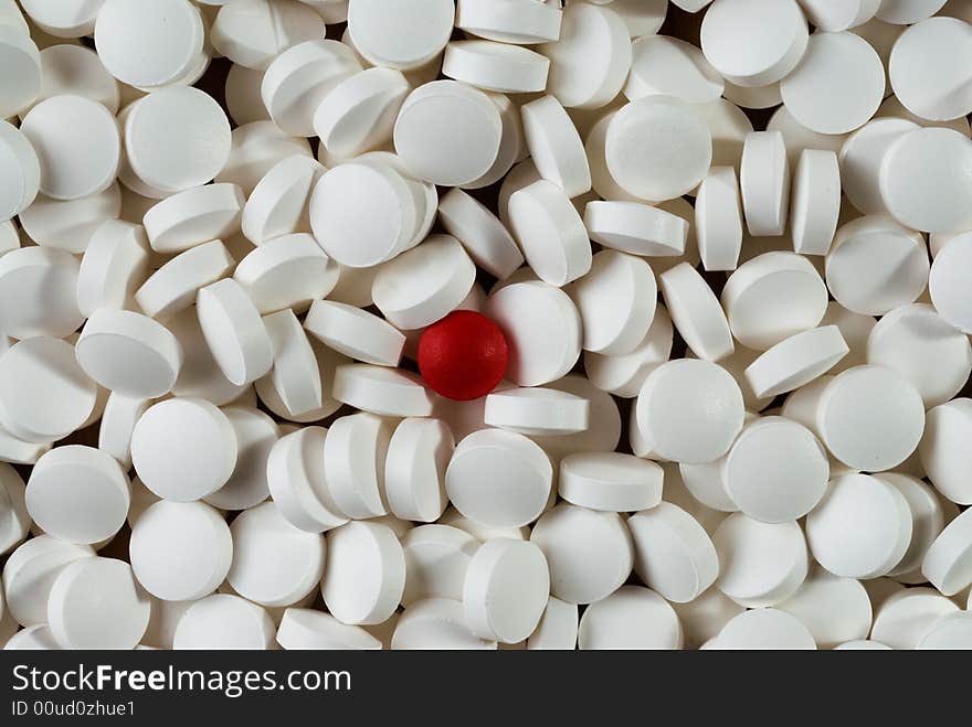 A lot of white pills with red pill in the middle. A lot of white pills with red pill in the middle