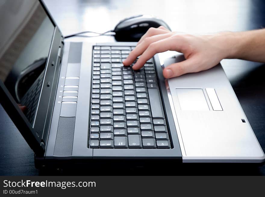 Male hand pushing the enter button on a laptop keyboard. Hand is out of focus!