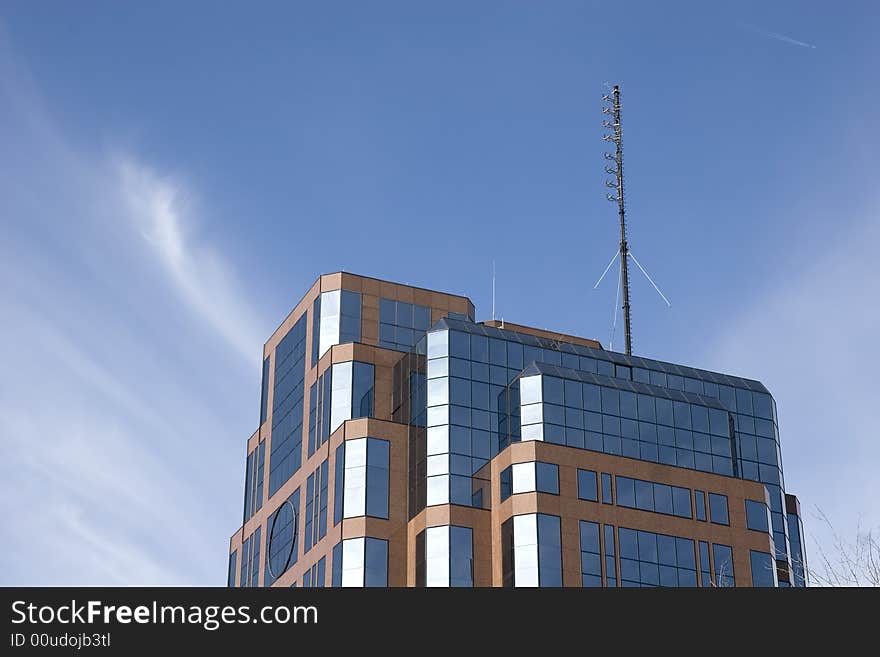 A nice brick and glass office building rising into a blue sky and puffy clouds. A nice brick and glass office building rising into a blue sky and puffy clouds