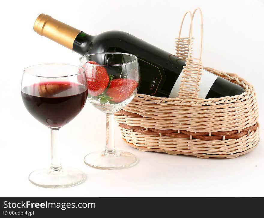 Wine glass with red wine and strawberry and wine bottle in the basket. Wine glass with red wine and strawberry and wine bottle in the basket