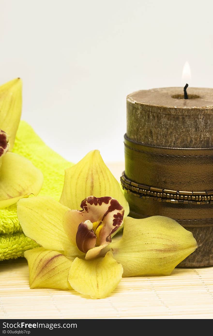 Spa essentials, candle with yellow orchids and towel