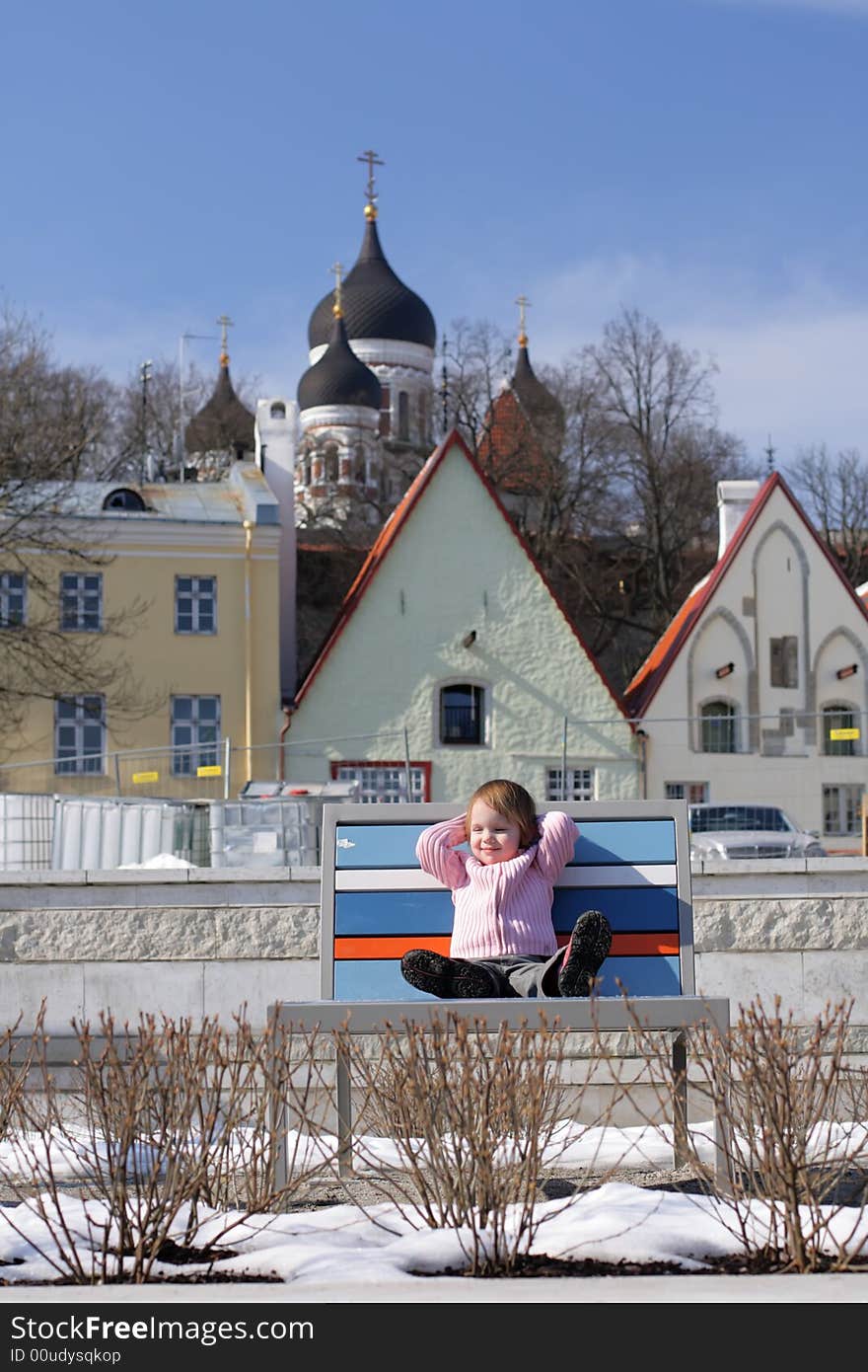 Early mild spring at  the center of Old Town little girl become sunburnt on chaise longue in the middle of snow