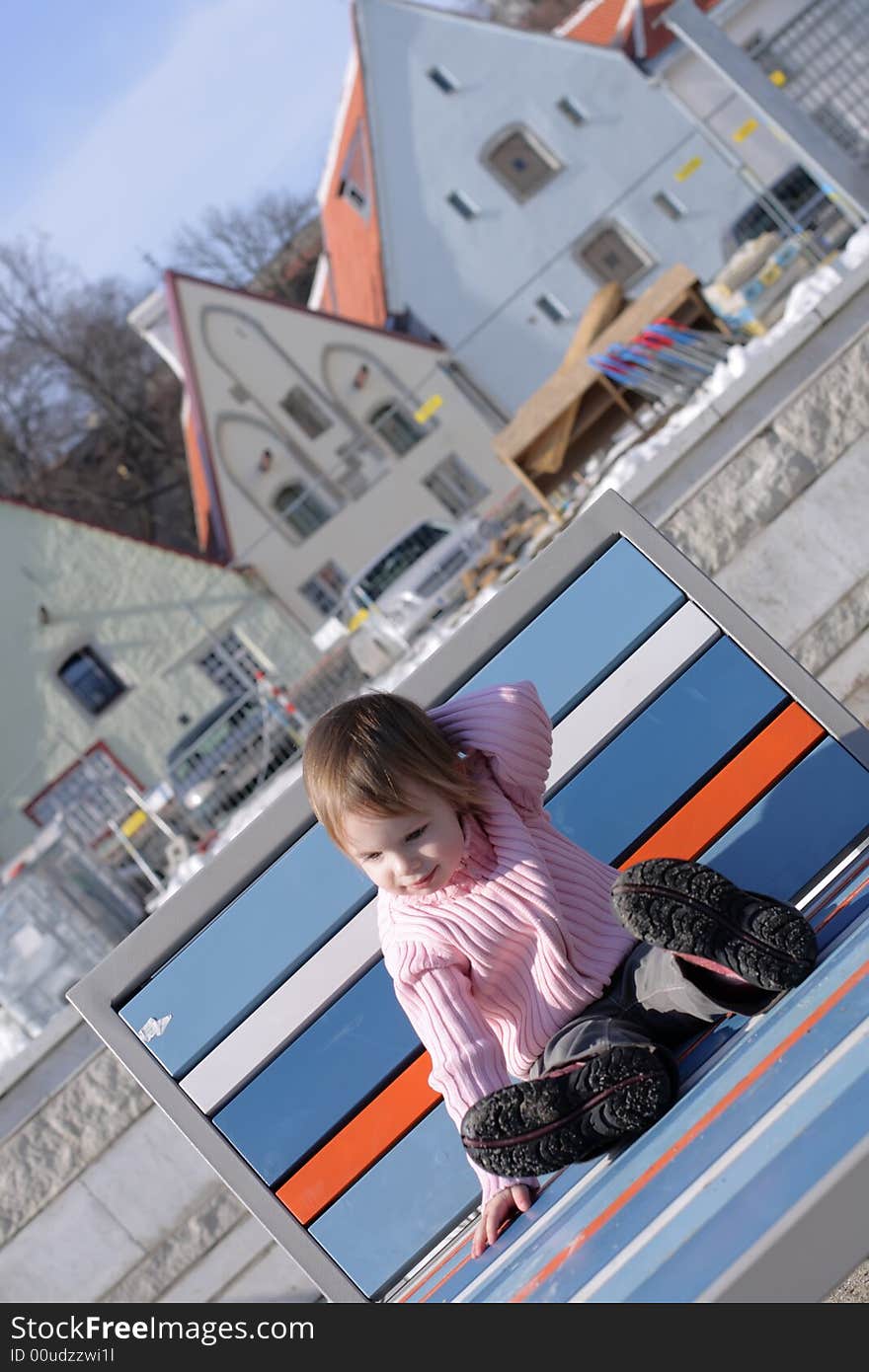 Early mild spring at  the center of Old Town little girl become sunburnt on chaise longue in the middle of snow. Early mild spring at  the center of Old Town little girl become sunburnt on chaise longue in the middle of snow