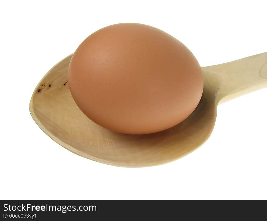 Close up to an egg on wooden spoon over white