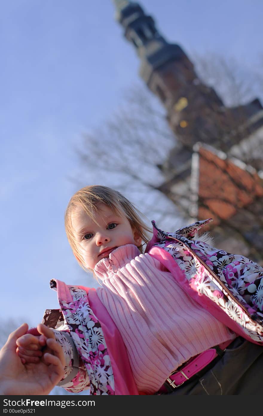 Ittle girl at the background of blue spring sky looking down on photographer or audience. Ittle girl at the background of blue spring sky looking down on photographer or audience