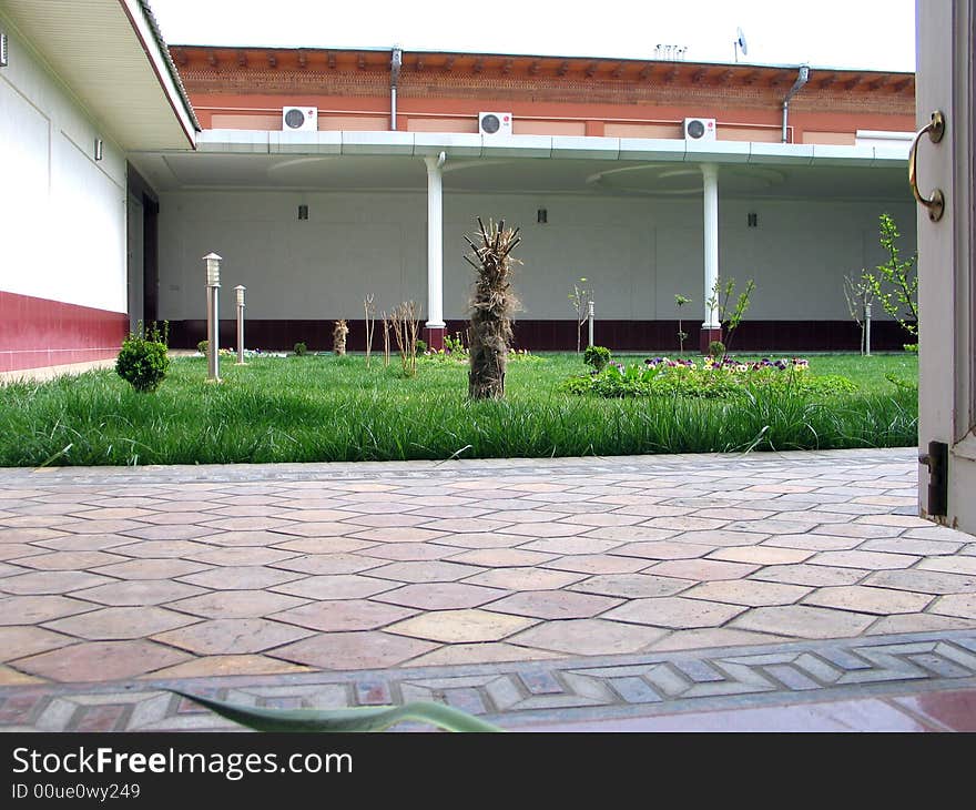 Green grass, wall with pillars on courtyard. Green grass, wall with pillars on courtyard