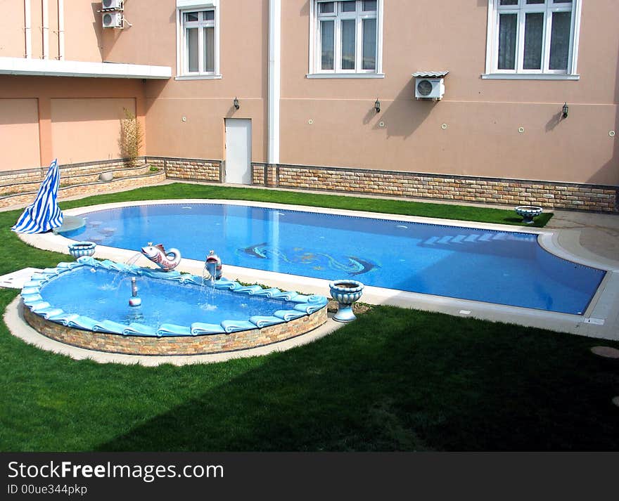 Green grass, cream-coloured wall and pool on courtyard. Green grass, cream-coloured wall and pool on courtyard