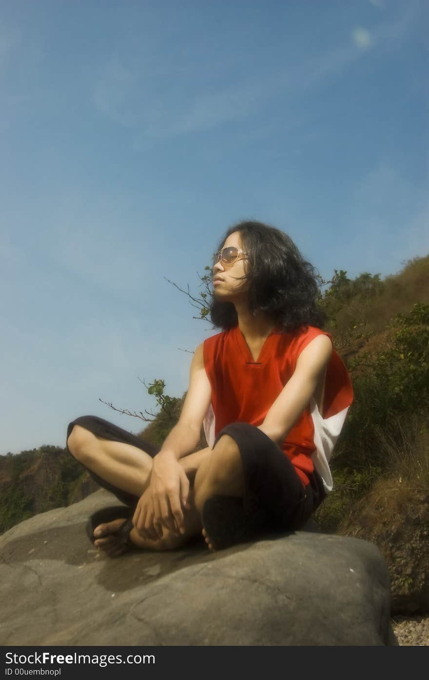 Young man sitting on rock by the beach. Young man sitting on rock by the beach