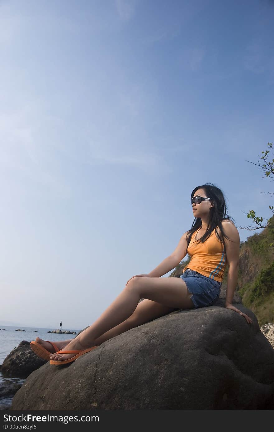 Asian woman on rock by the beach