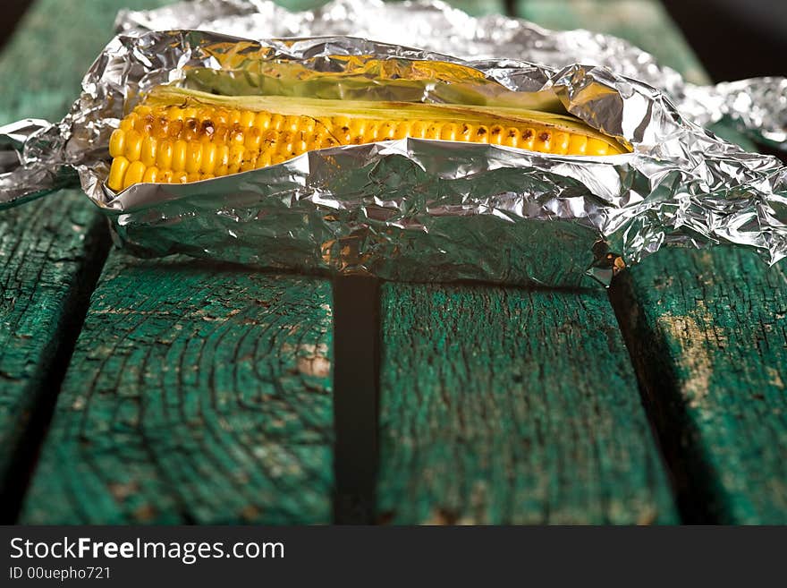 Sweetcorn wrapped in foil on a green bench