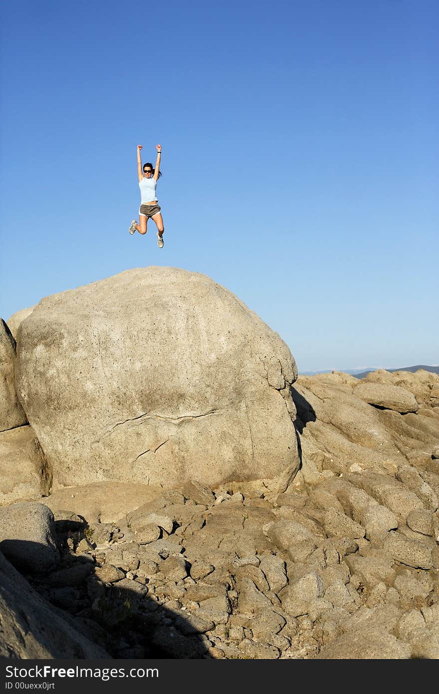 A woman jumps for joy when she reaches the top of the hill. A woman jumps for joy when she reaches the top of the hill