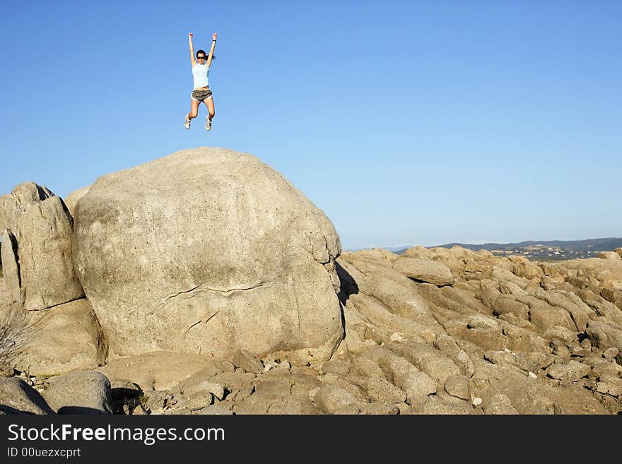 A woman jumps for joy when she reaches the top of the hill. A woman jumps for joy when she reaches the top of the hill