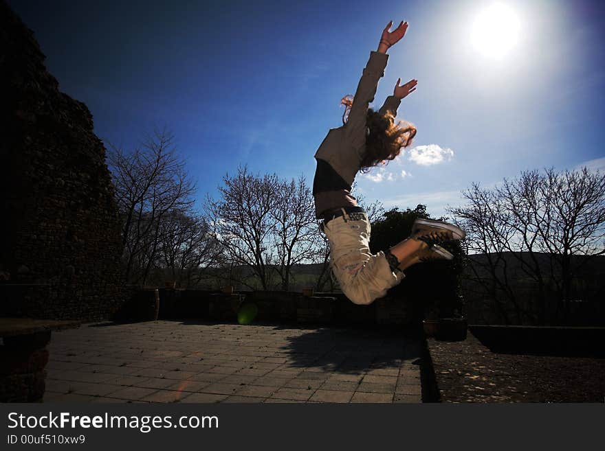 A girl jumping before bright sunny blue sky. A girl jumping before bright sunny blue sky