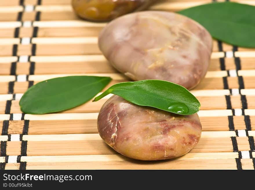 Spa stones and green leaves on bamboo