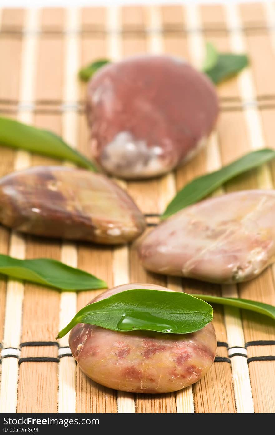 Spa stones and green leaves on bamboo