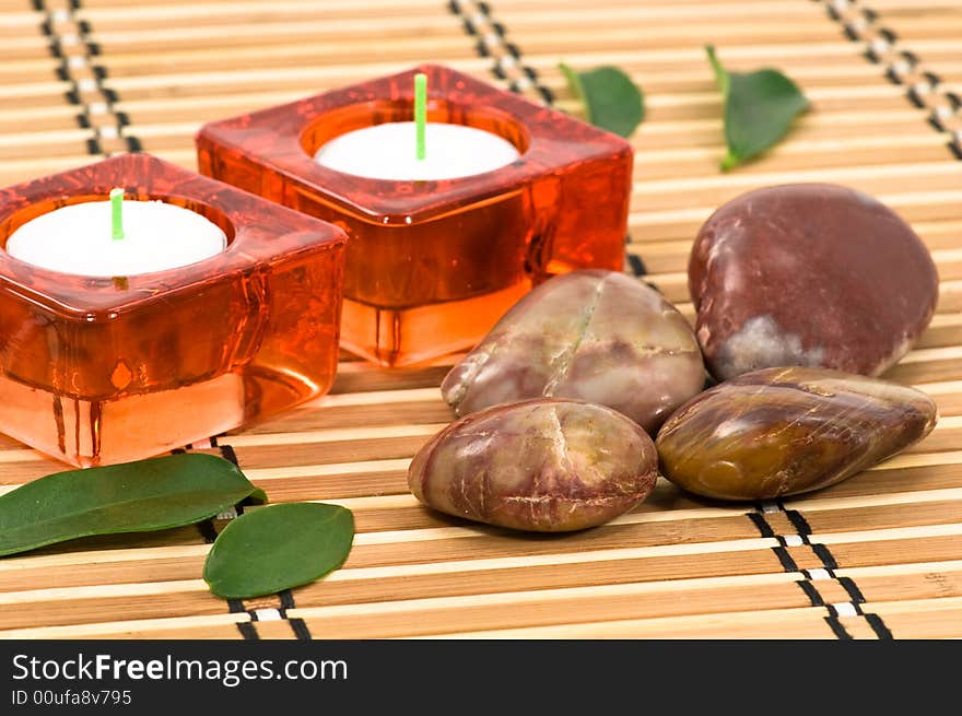 Spa stones, candles and green leaves on bamboo. Spa stones, candles and green leaves on bamboo