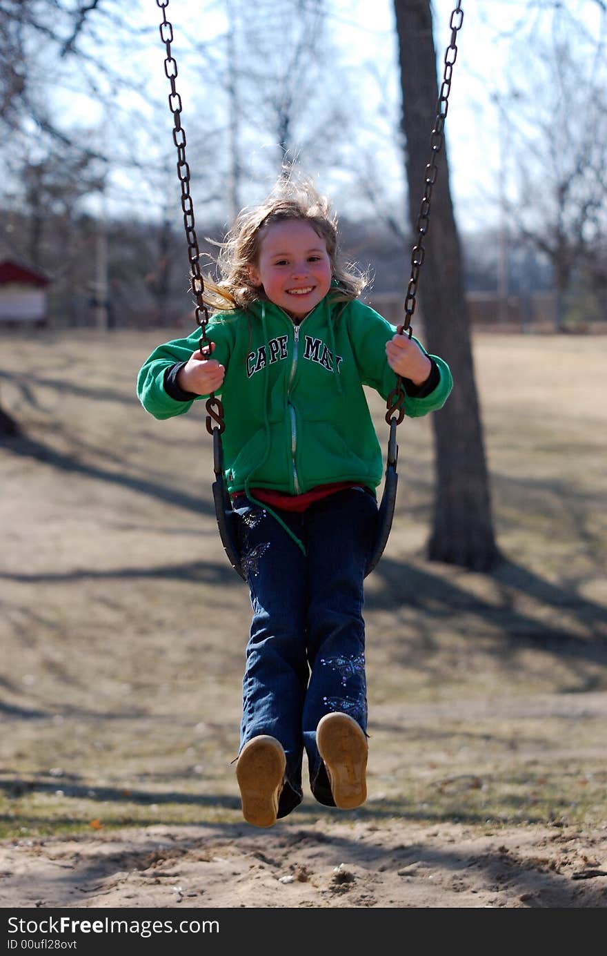 A pretty smiling blonde girl mid-air on a swing. A pretty smiling blonde girl mid-air on a swing.