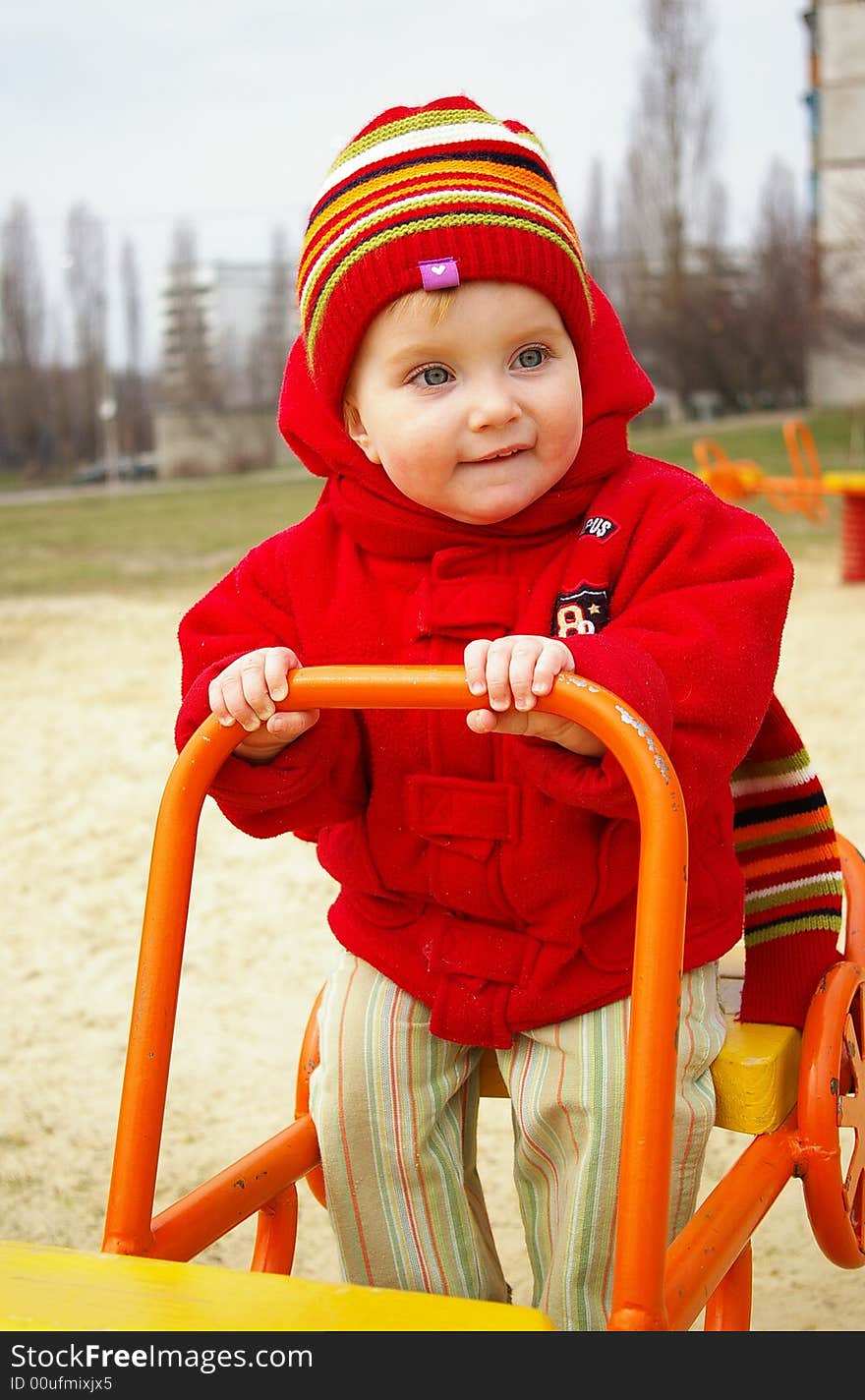 Laughing girl in a red jacket goes for a drive on a swing. Laughing girl in a red jacket goes for a drive on a swing