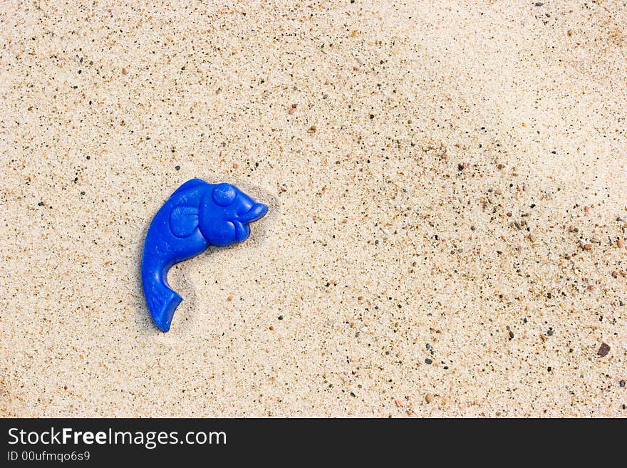 Lost toy fish on a sandy beach