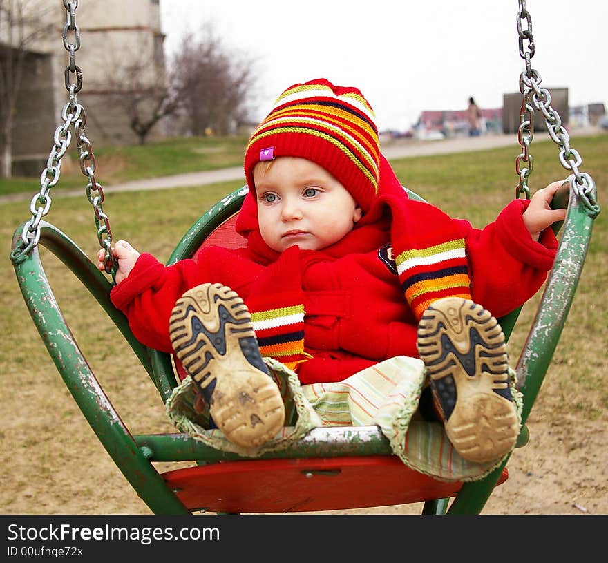 The sad girl in a red jacket goes for a drive on a swing. The sad girl in a red jacket goes for a drive on a swing