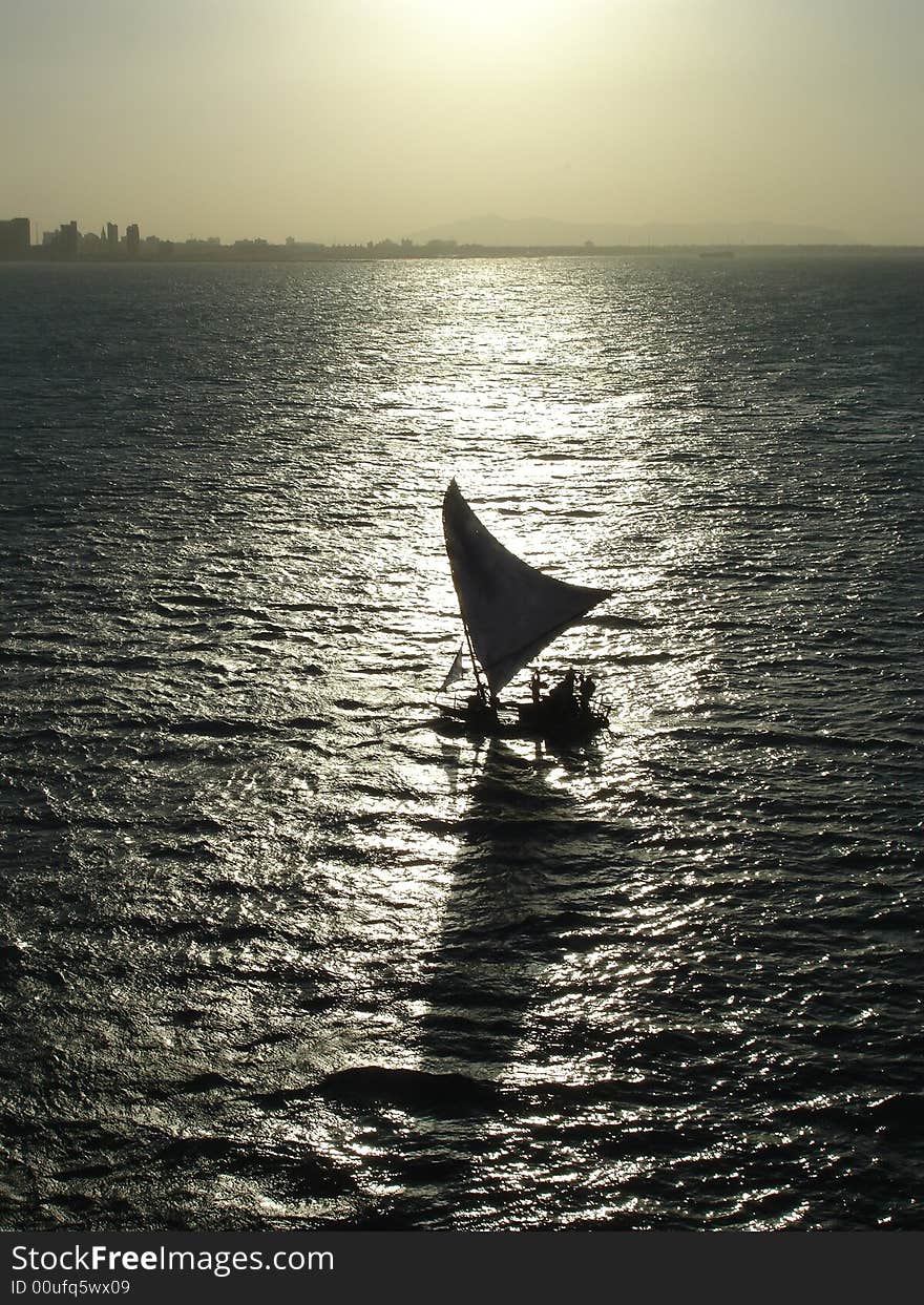 A sail boat silhouette and reflection.