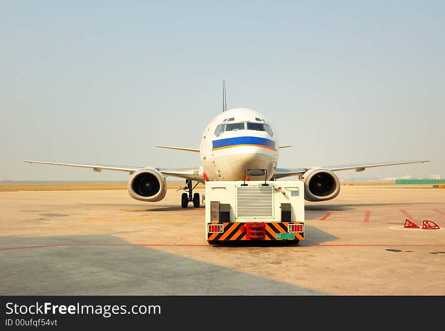 Traction aircraft equipment is pushing the plane took off at the airport runway. Traction aircraft equipment is pushing the plane took off at the airport runway