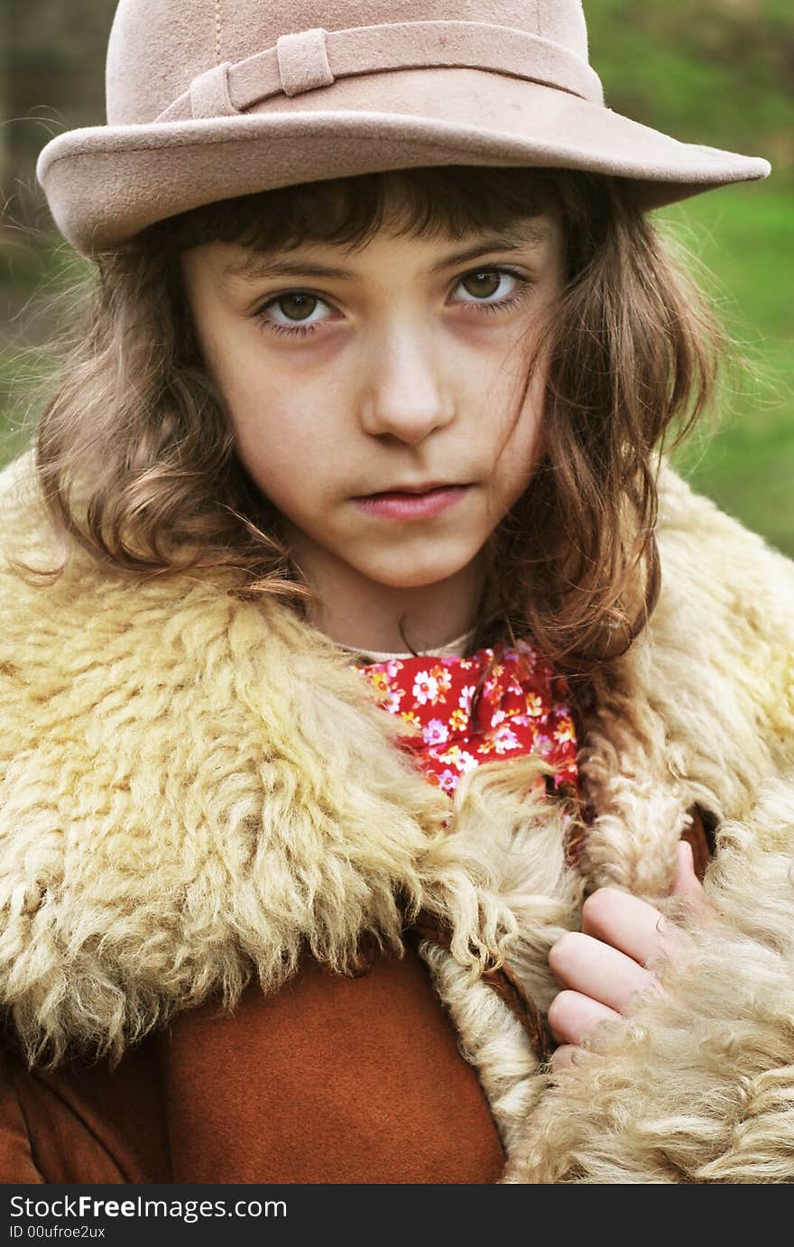 Little sad girl wearing a hat and vintage winter fur coat. Little sad girl wearing a hat and vintage winter fur coat