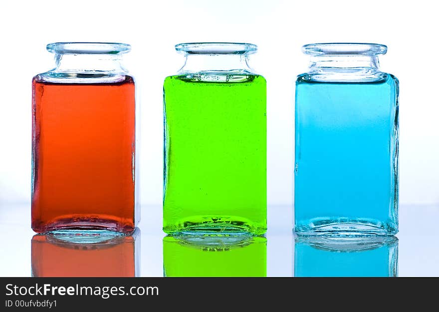 Three glass bottles containing different color liquids: reed, green, blue. Three glass bottles containing different color liquids: reed, green, blue